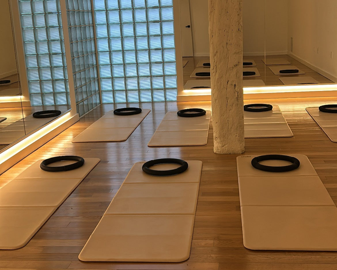 Yoga mats with black rings on a wooden floor in a room with glass block walls.
